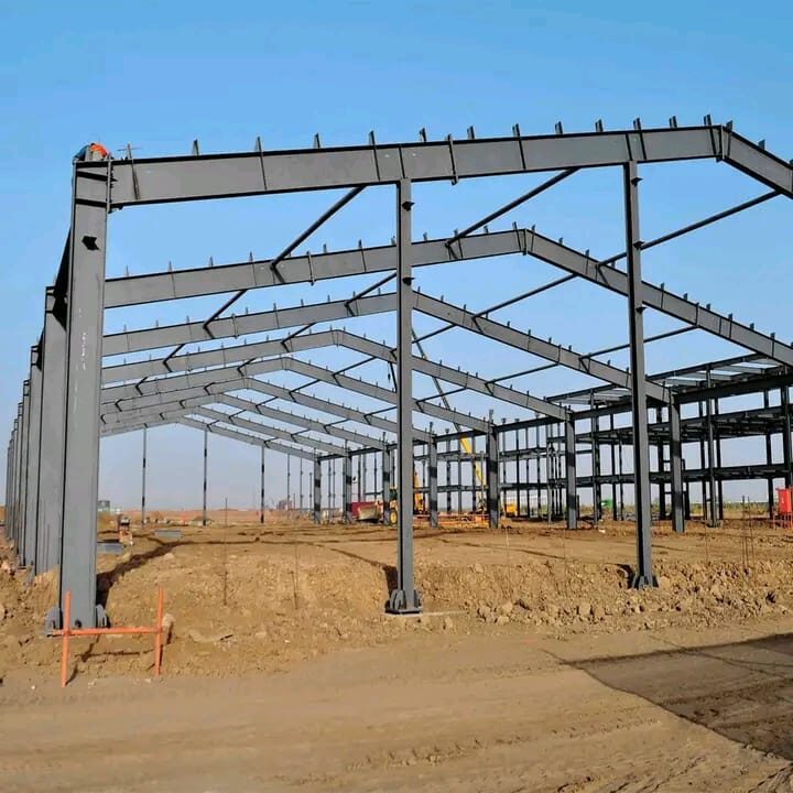 Structural steel portal frame under construction against a clear sky